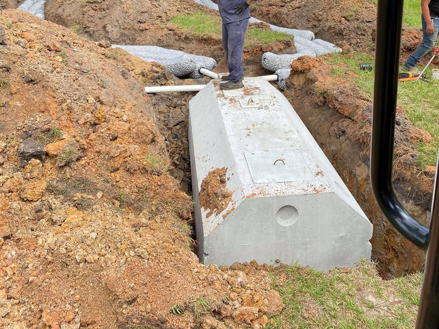 A man is standing on top of a large concrete block in the dirt.