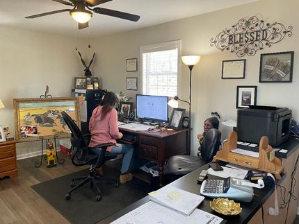 A woman is sitting at a desk in a home office.