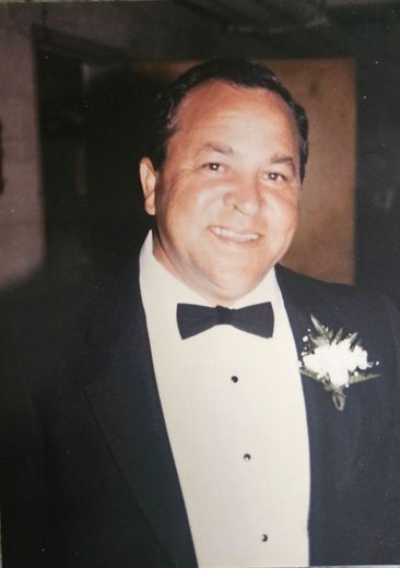 A man in a tuxedo and bow tie is smiling for the camera.