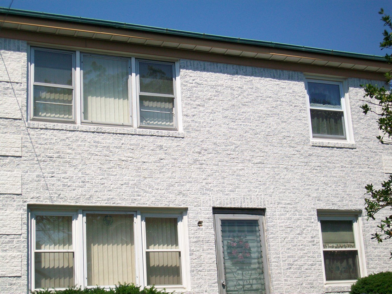 A white brick house with a green roof