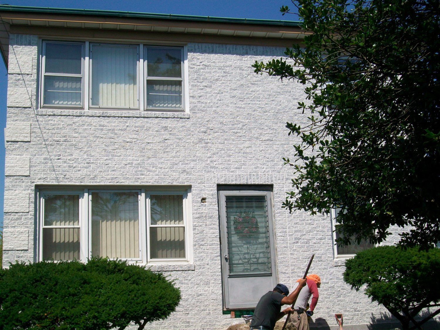 A man is standing in front of a white brick building