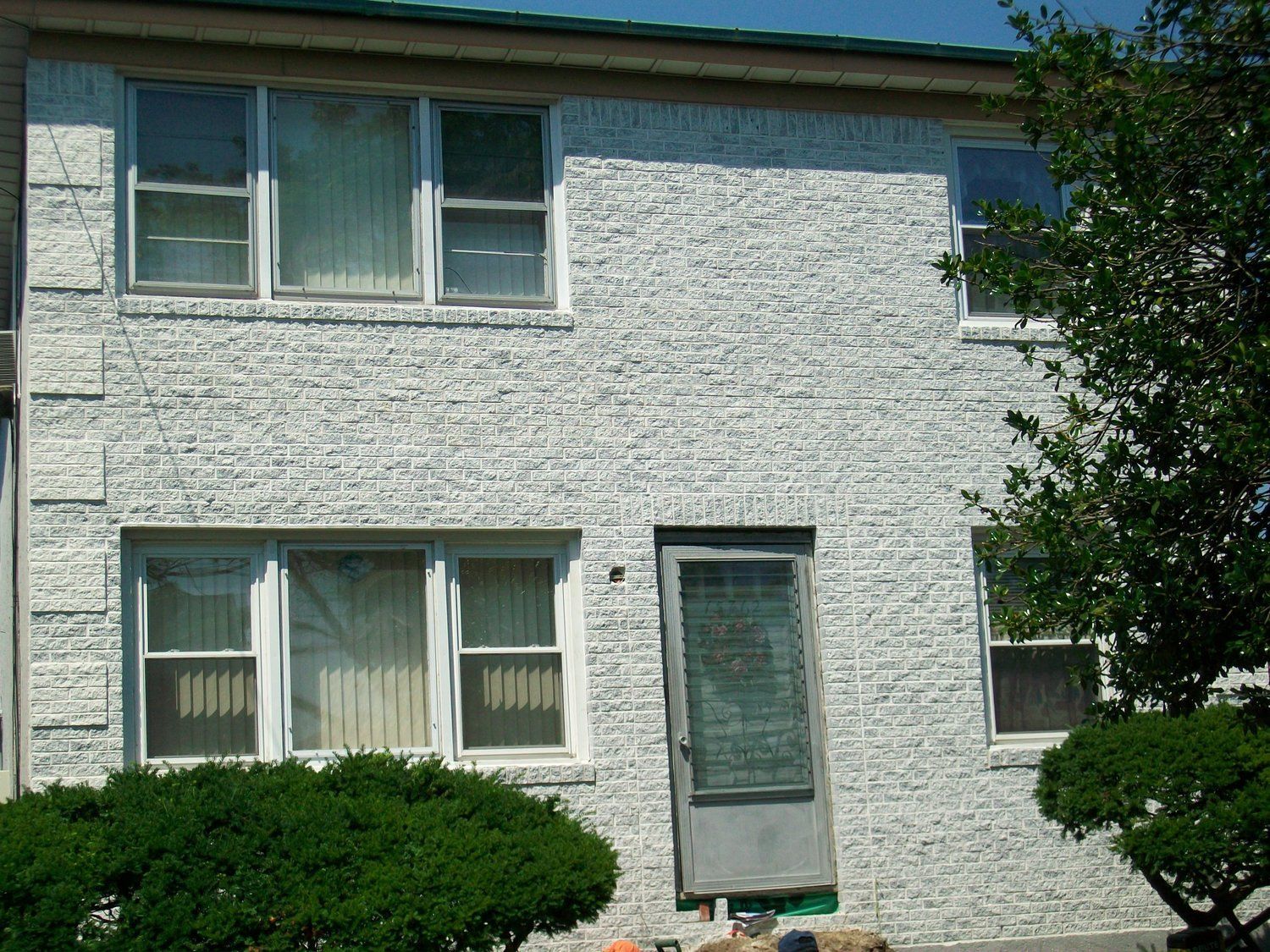 A white brick house with a green roof