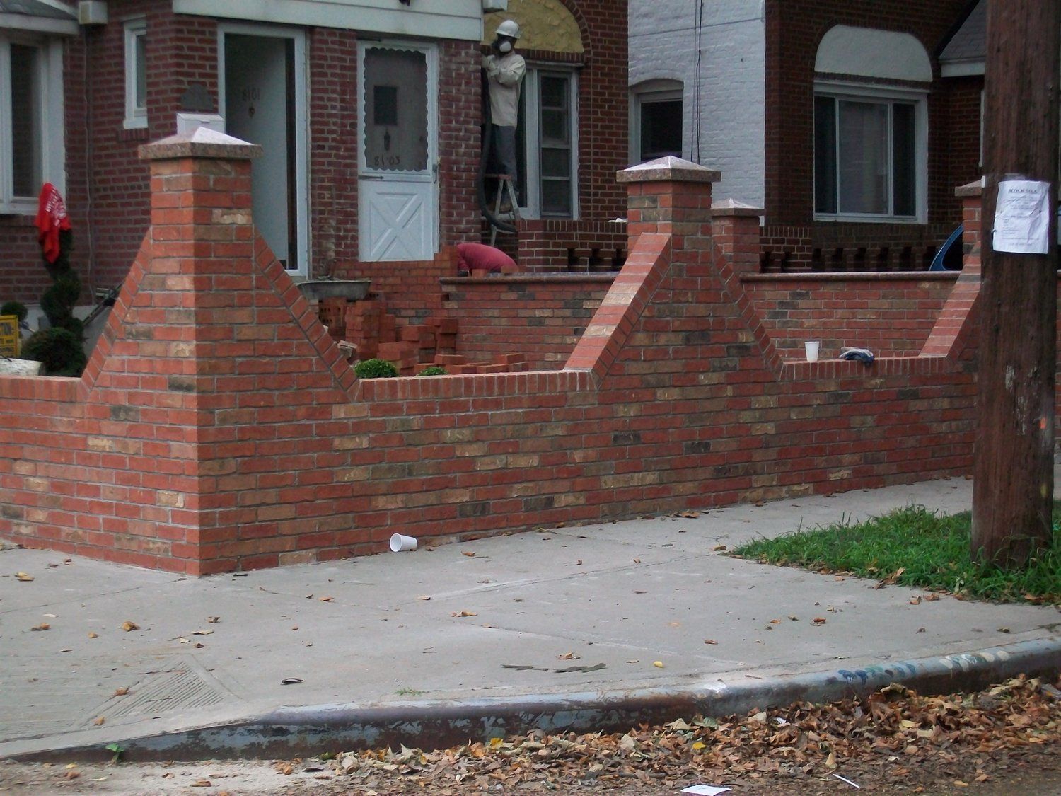 A brick wall is in front of a brick house