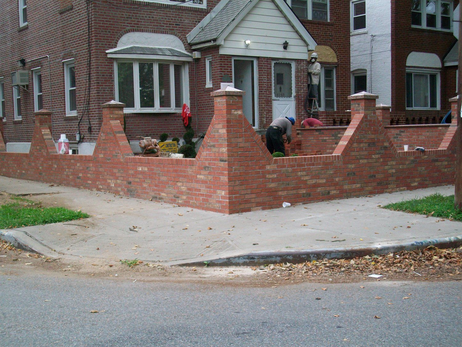 A man is working on a brick wall in front of a house