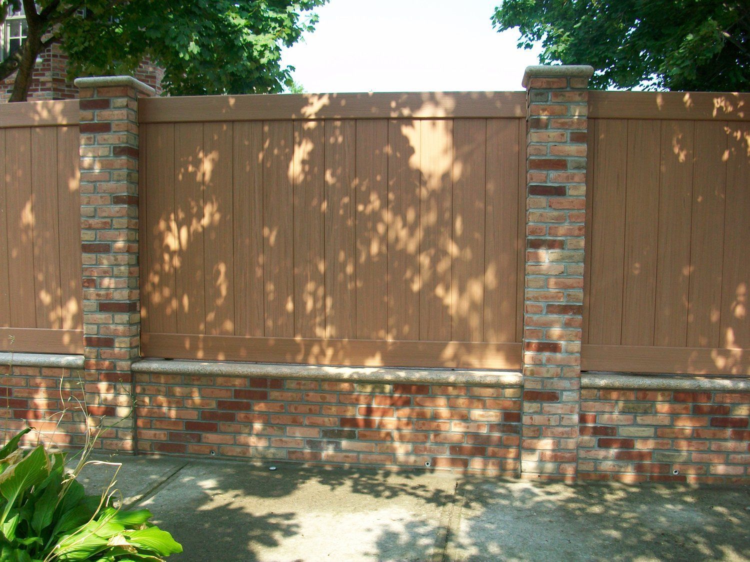 A wooden fence is surrounded by brick pillars