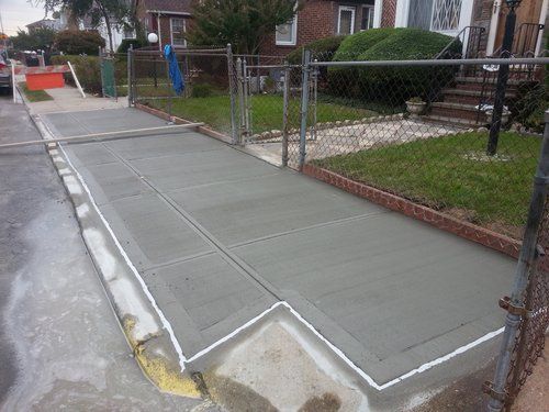 A concrete walkway is being built in front of a house