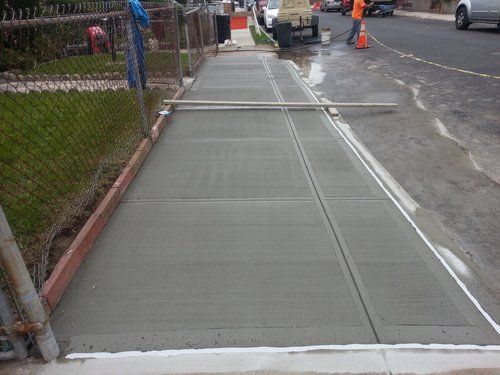 A concrete sidewalk is being built on the side of the road