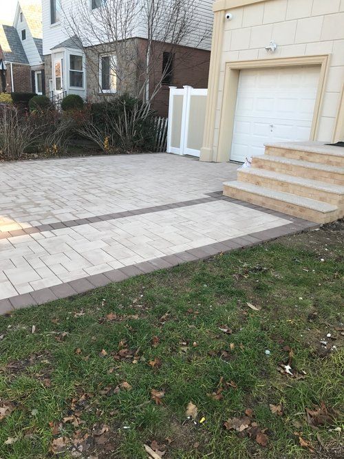 A driveway with steps leading to a garage and a house in the background.