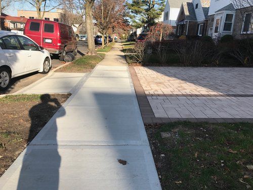 A sidewalk with a red van parked on the side of it