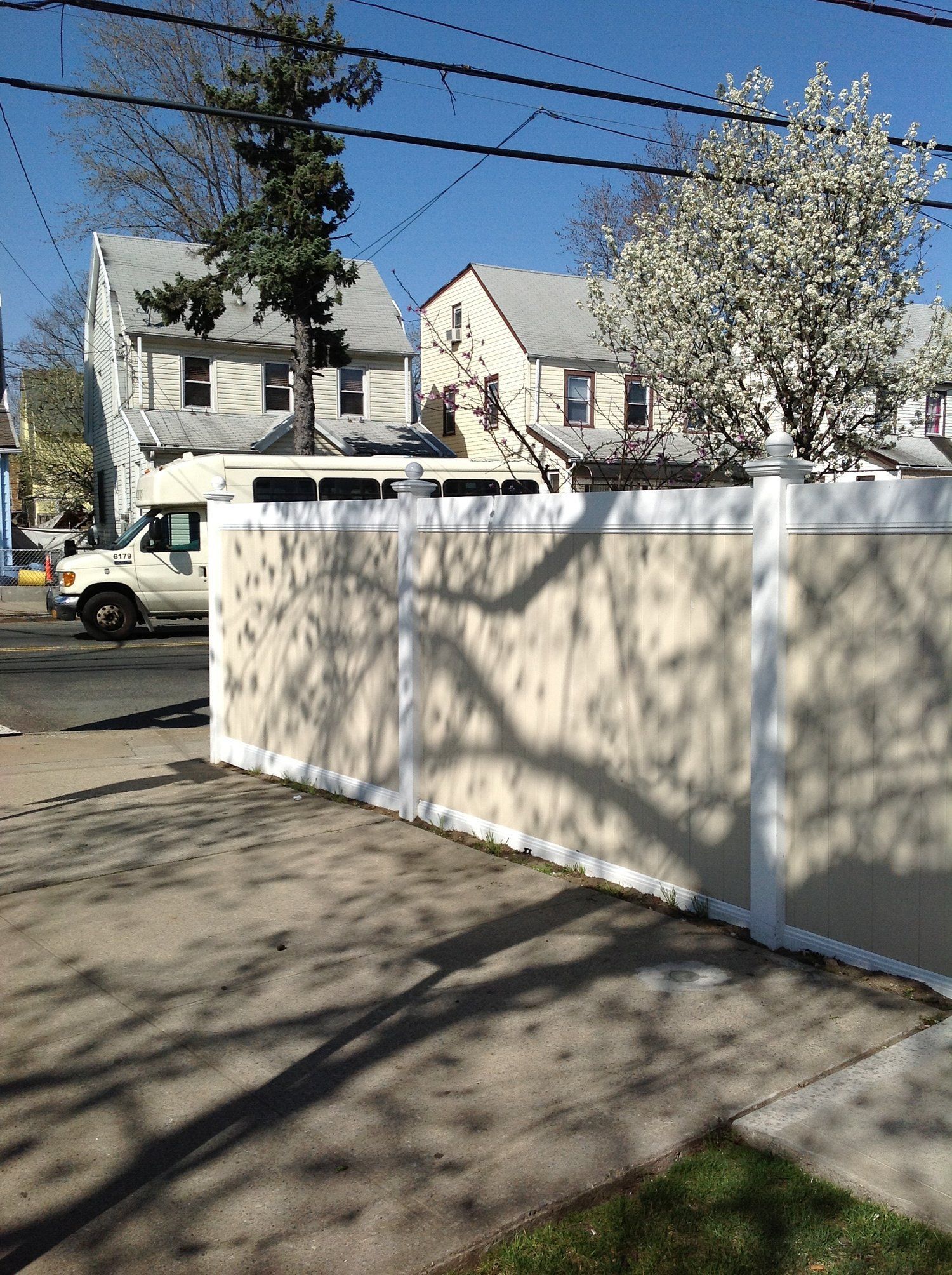 A white van is parked in front of a white fence
