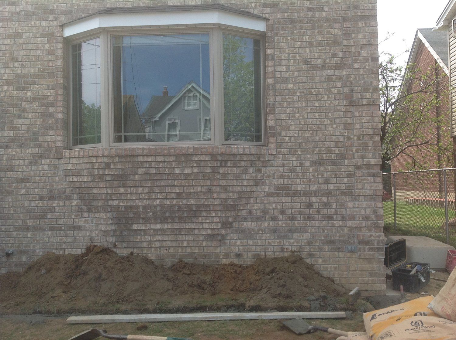 A brick building with a large window and a pile of dirt in front of it