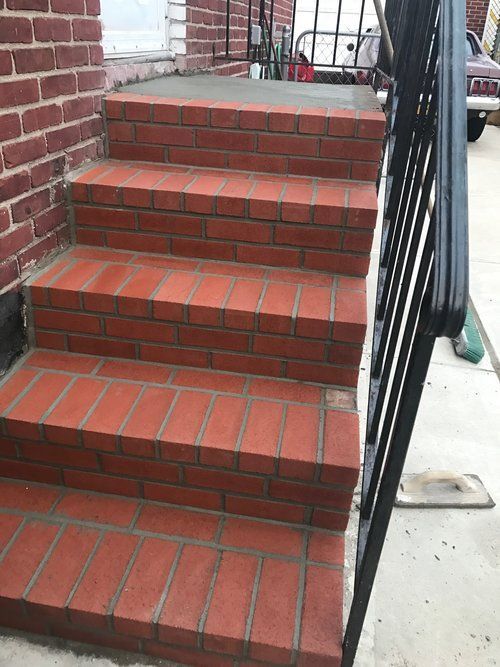 A set of red brick stairs leading up to a brick building