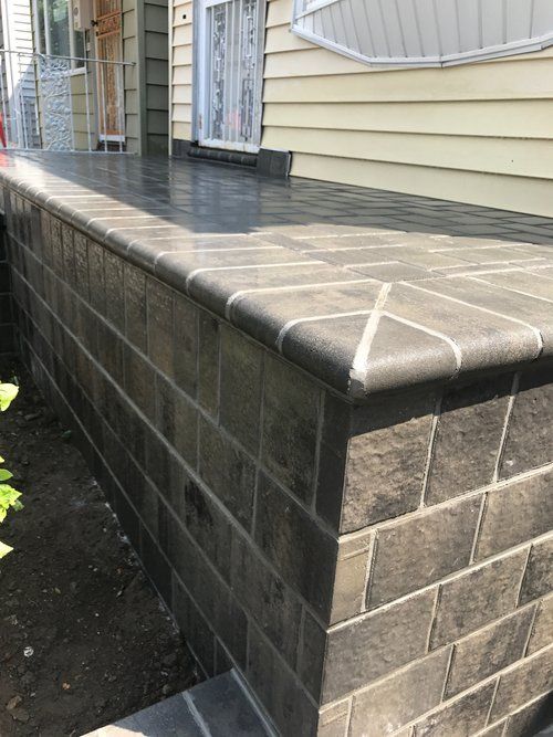 A brick wall with a concrete patio in front of a house.