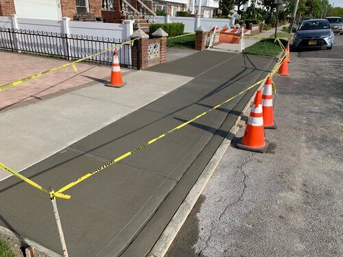 A concrete sidewalk with orange and white cones on it