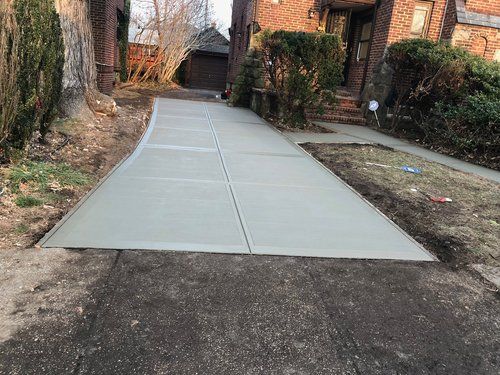 A concrete driveway is being built in front of a brick house.