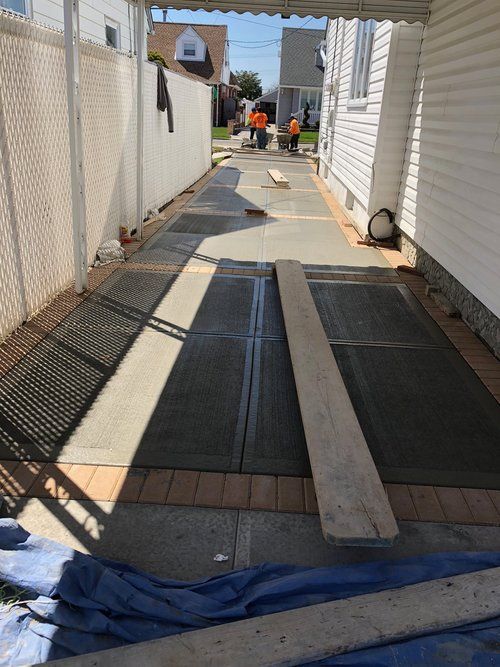A concrete walkway is being built in the backyard of a house.