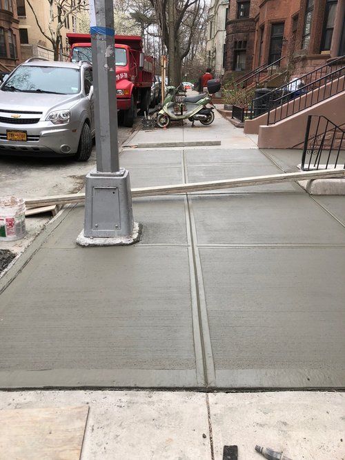 A car is parked on the side of the road next to a concrete sidewalk.