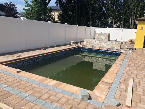 An empty swimming pool with a white fence in the background