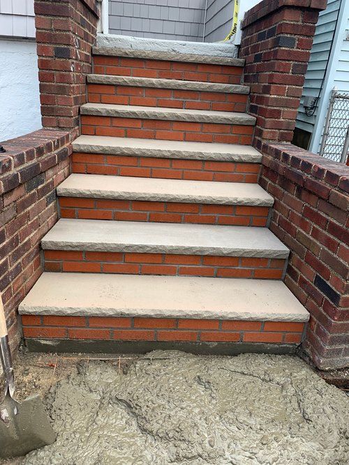A set of brick stairs with concrete steps and a brick wall.