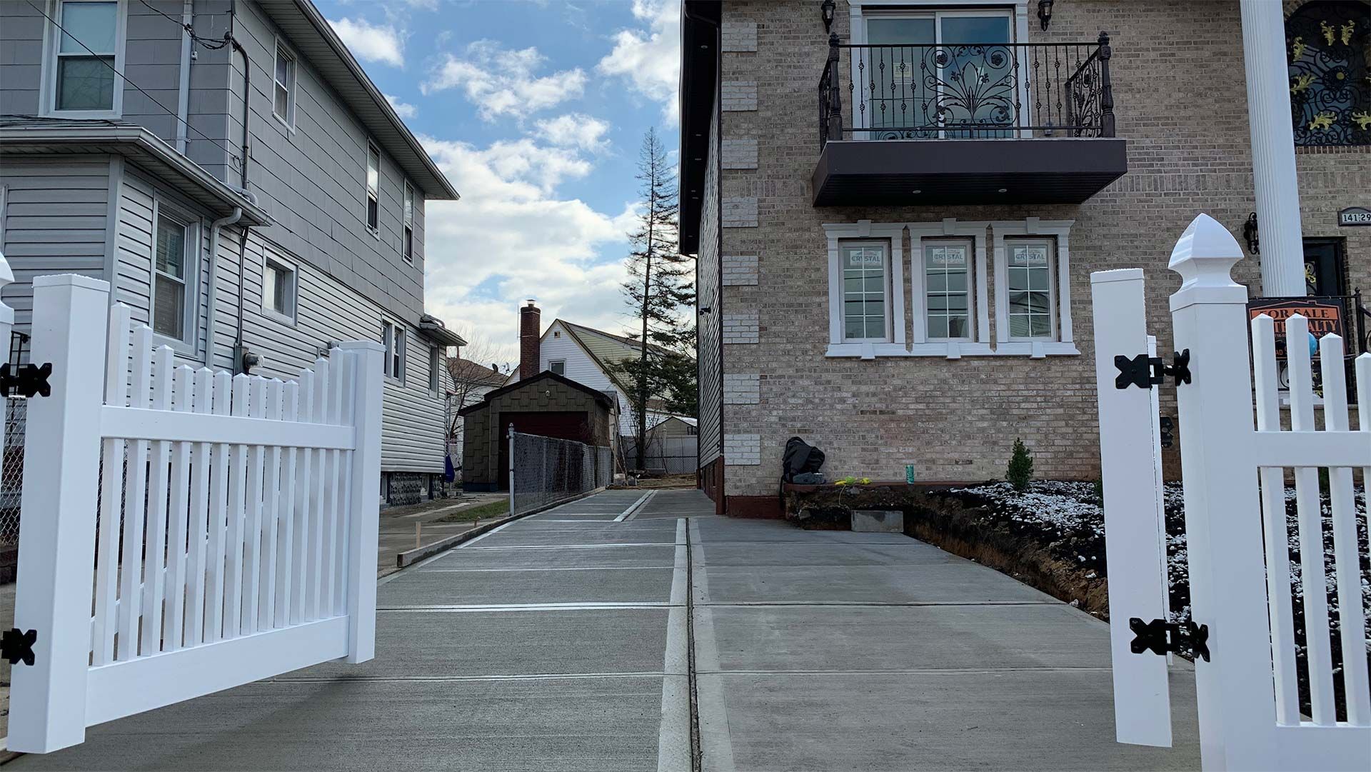 A white picket fence is open in front of a brick house
