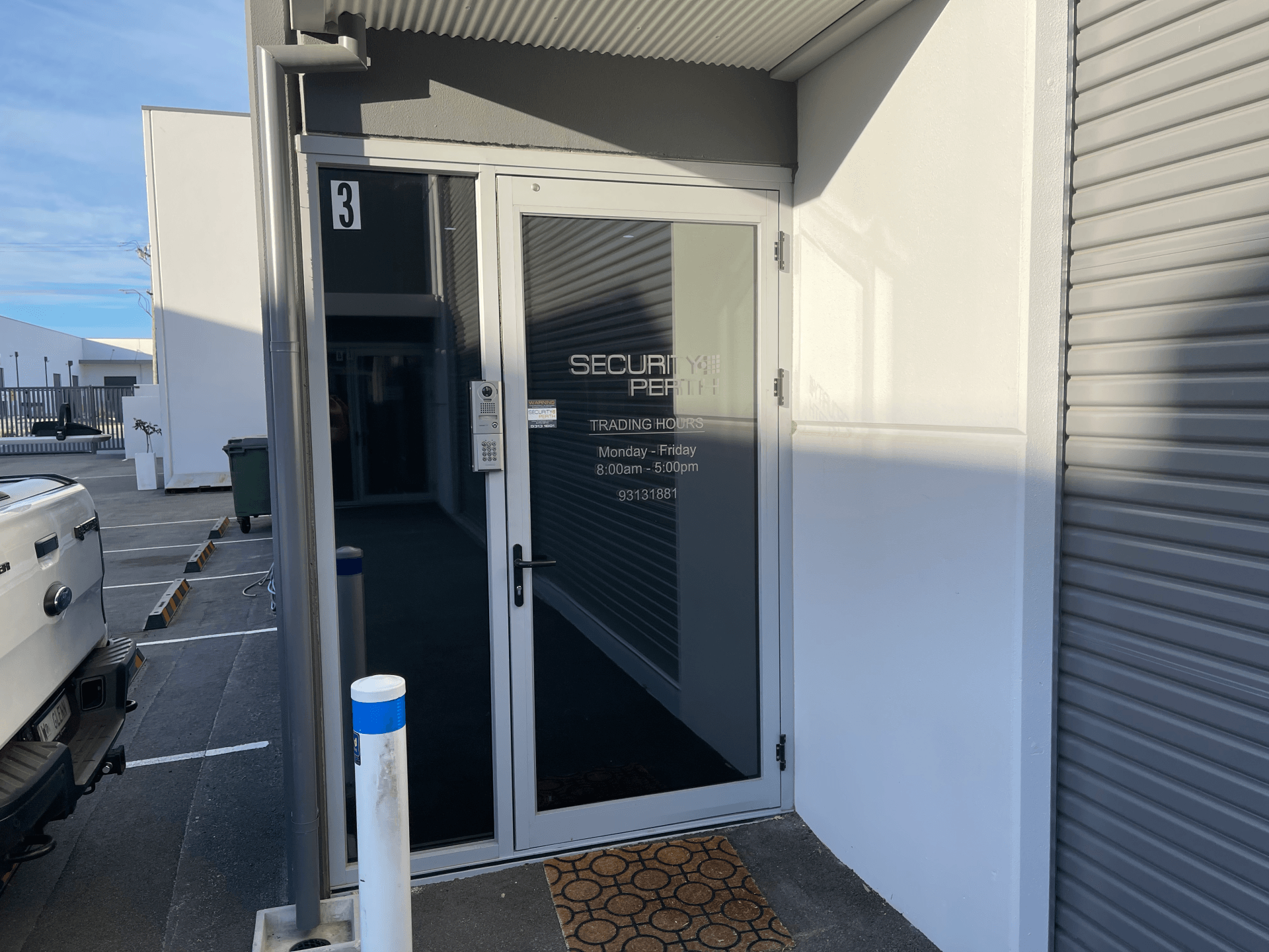 A white building with a glass door and a sign on it.