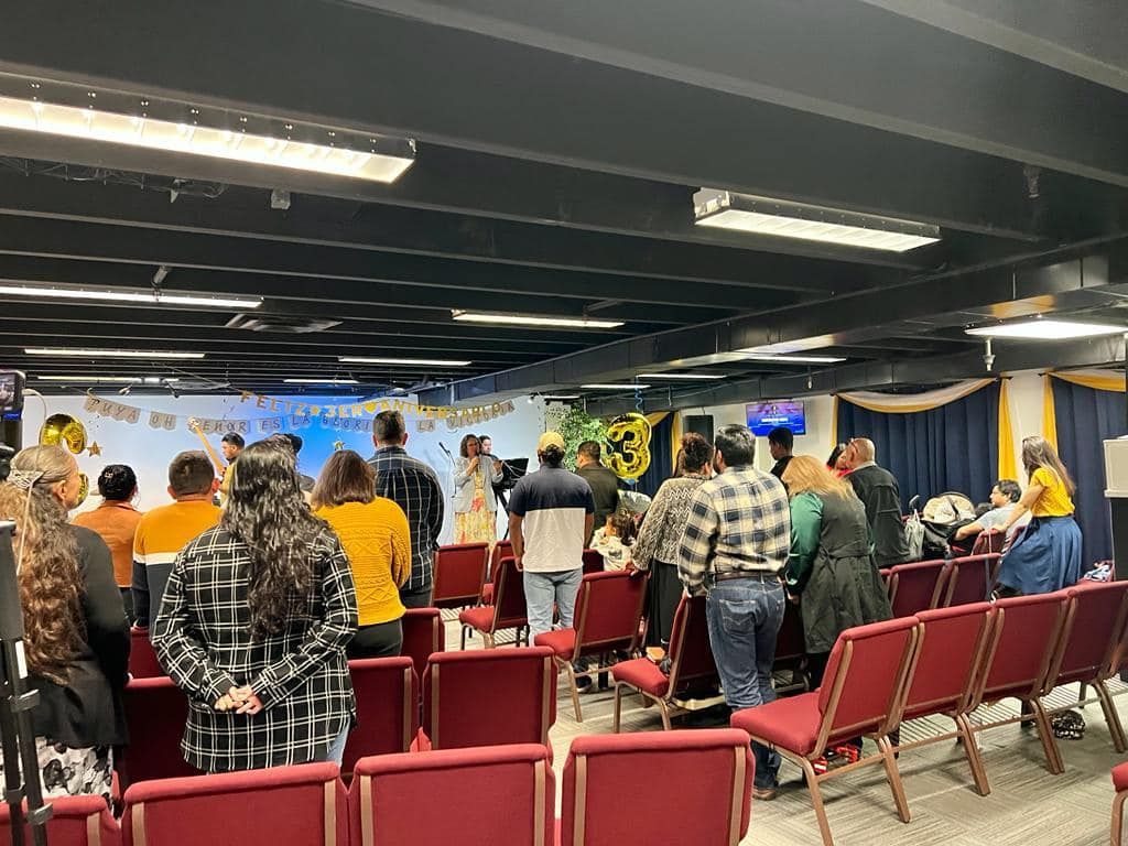 Un grupo de personas están sentadas en sillas en una iglesia.