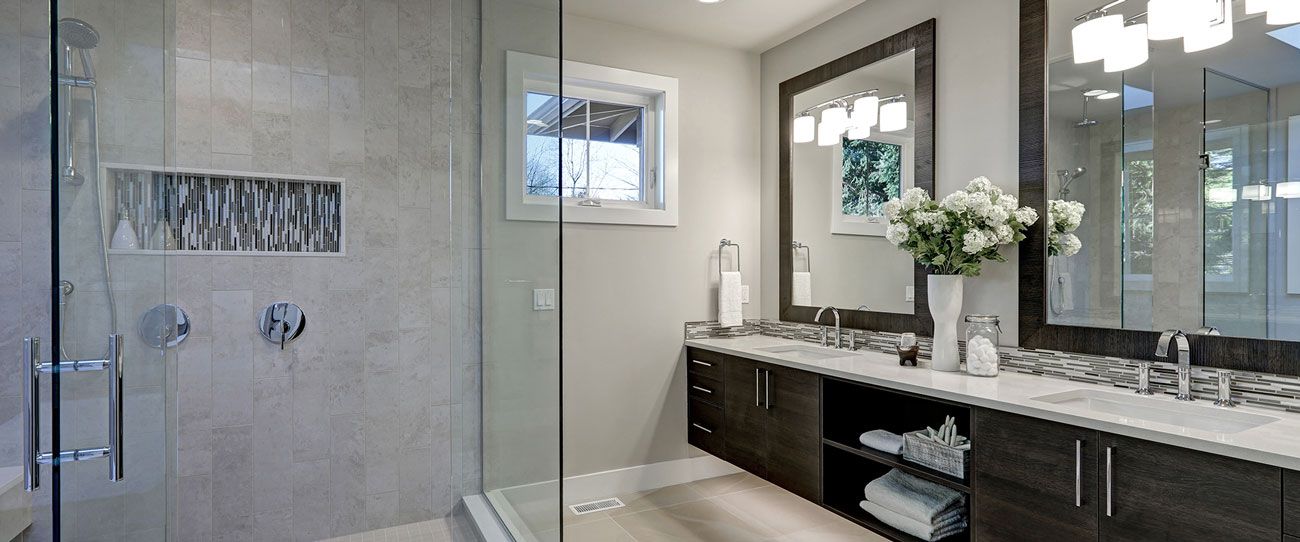 Modern bathroom with a glass shower, double vanity, and window.
