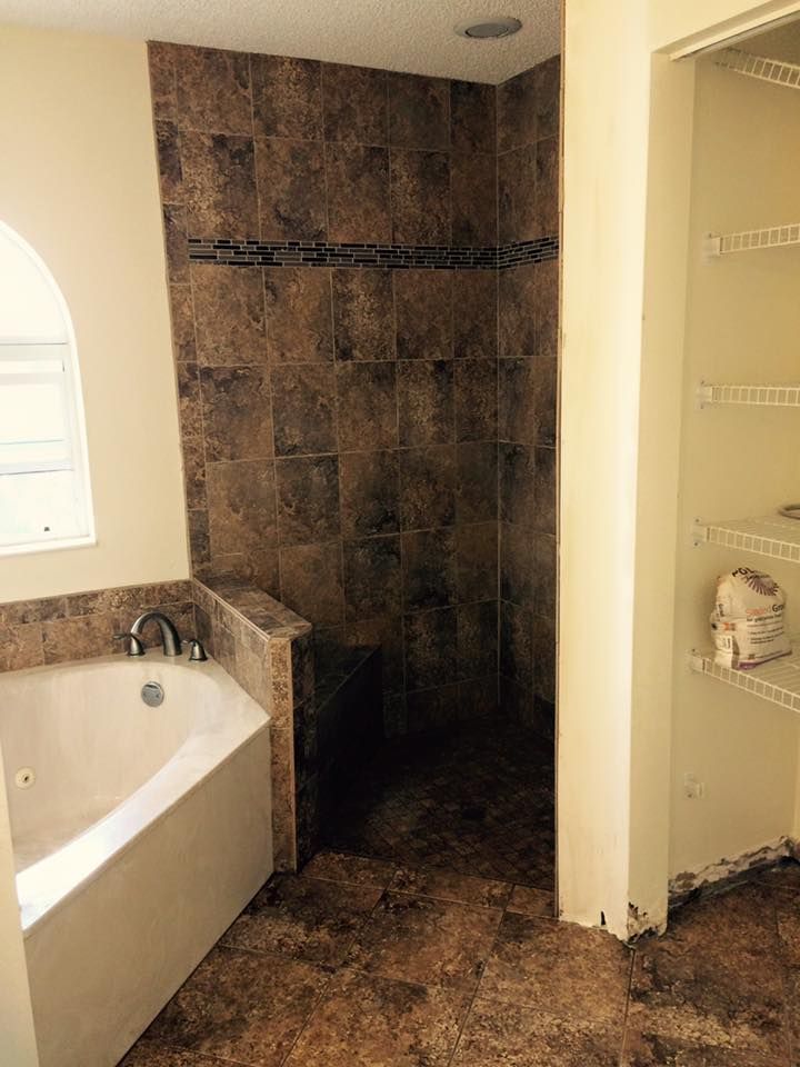 Bathroom with a tile shower, a corner tub, and a shelving unit.