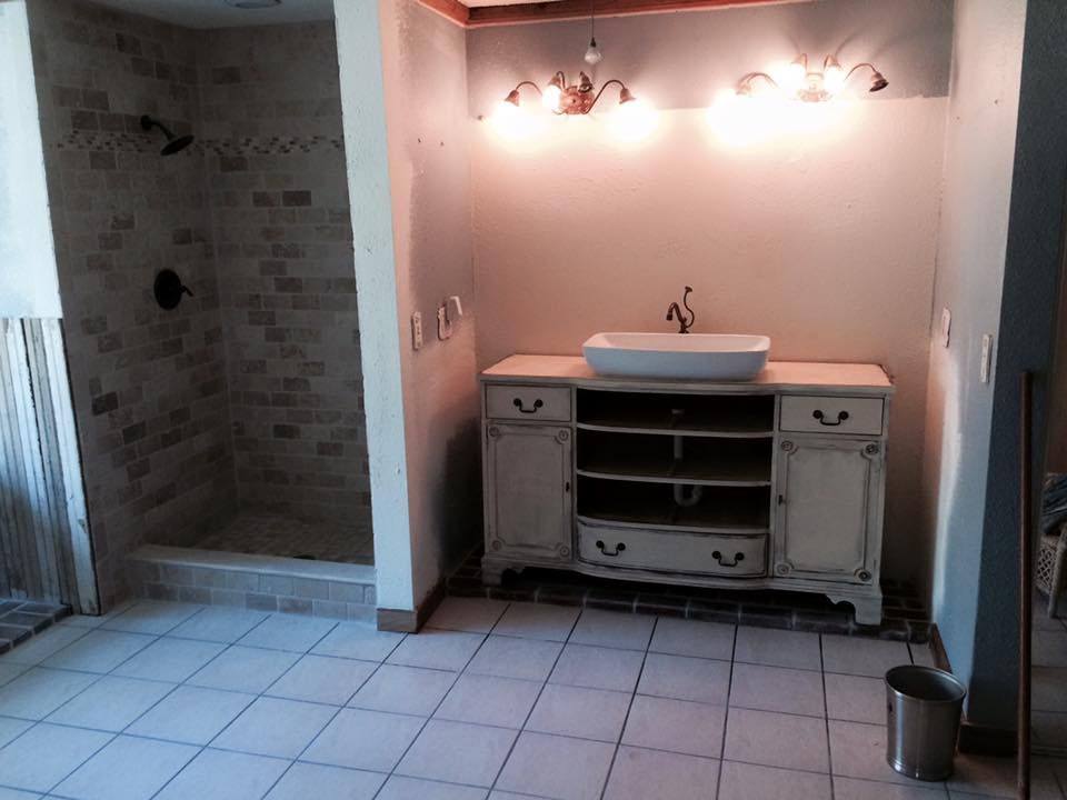 Bathroom renovation: beige vanity with vessel sink, tiled shower, and light-colored tile floor.