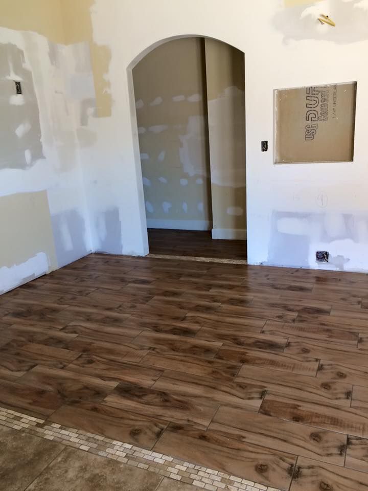 Room with wood-look tile flooring, an arched doorway, and unfinished walls.
