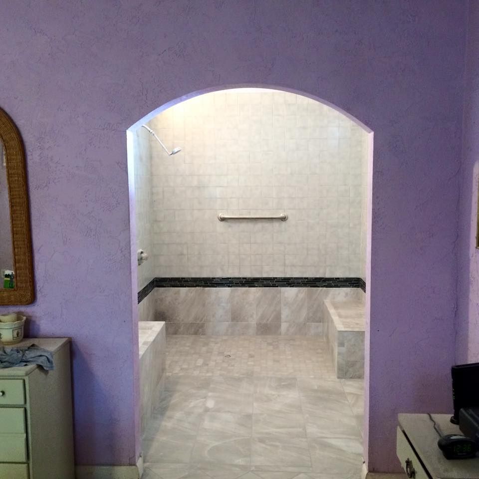 Purple-walled bathroom with arched doorway leading to a tiled shower area.