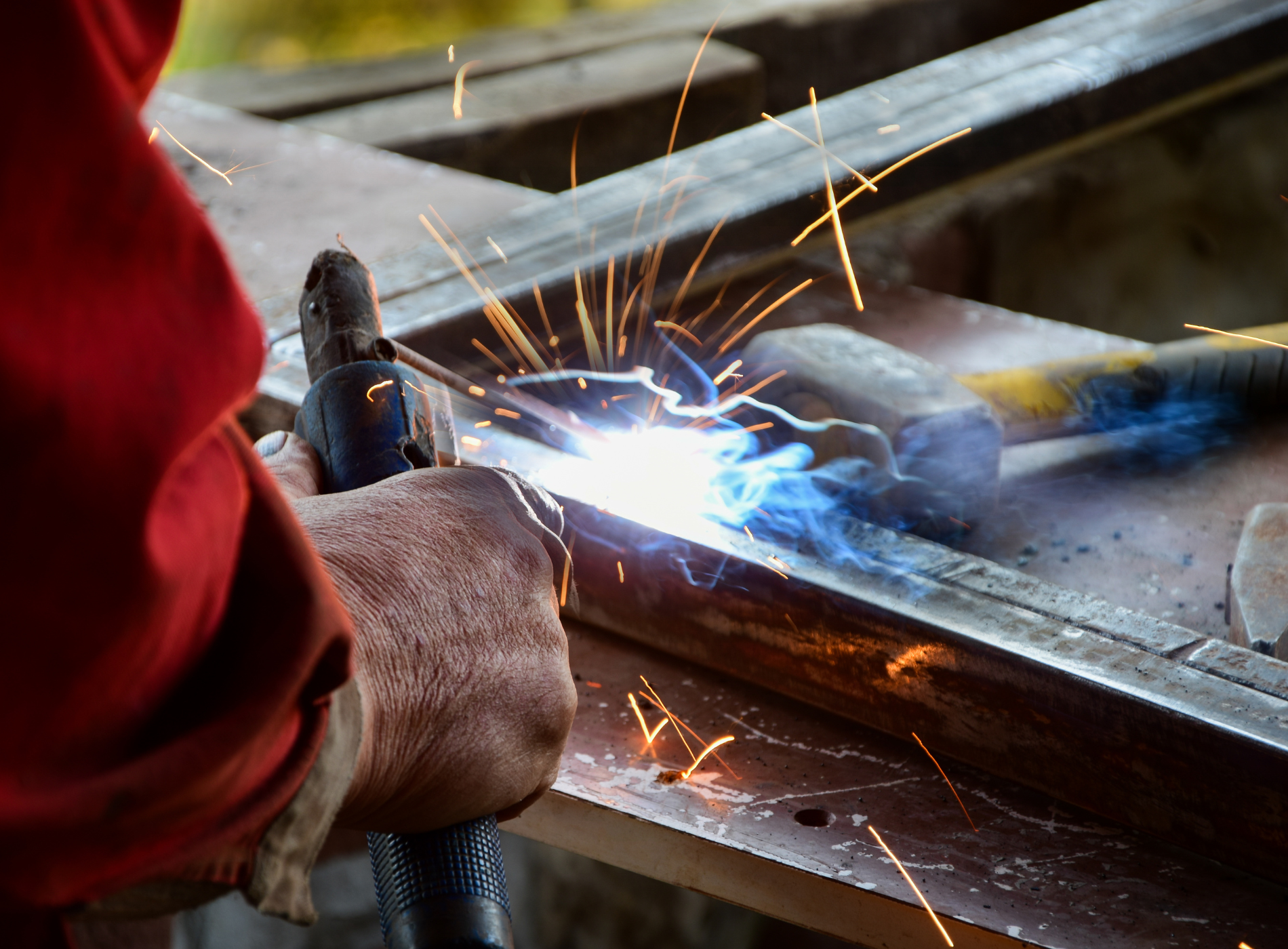 A person is welding a piece of metal on a table.