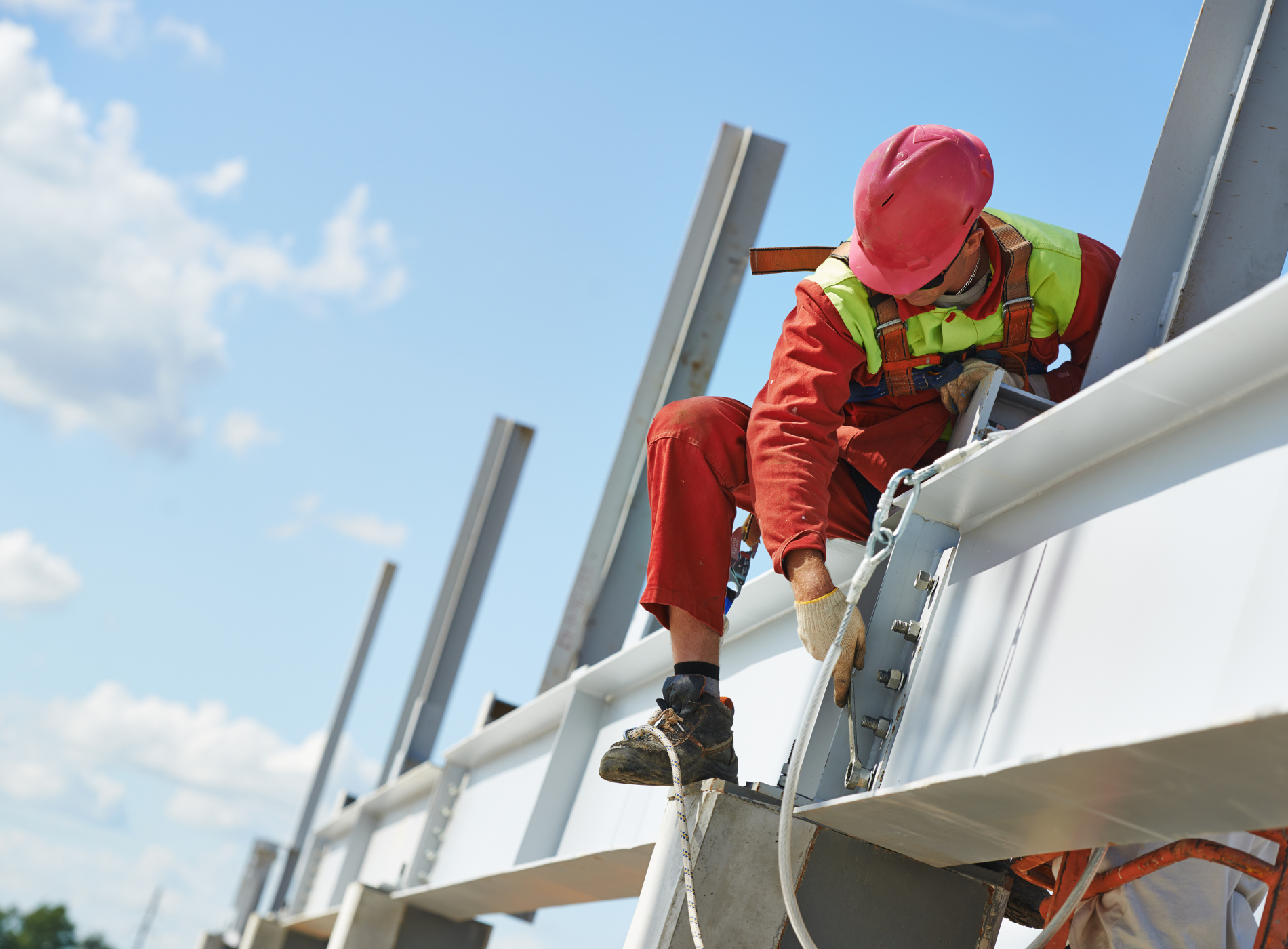 A construction worker is sitting on top of a metal structure.