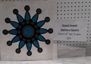 A stained glass applique square with a blue and black design on it.
