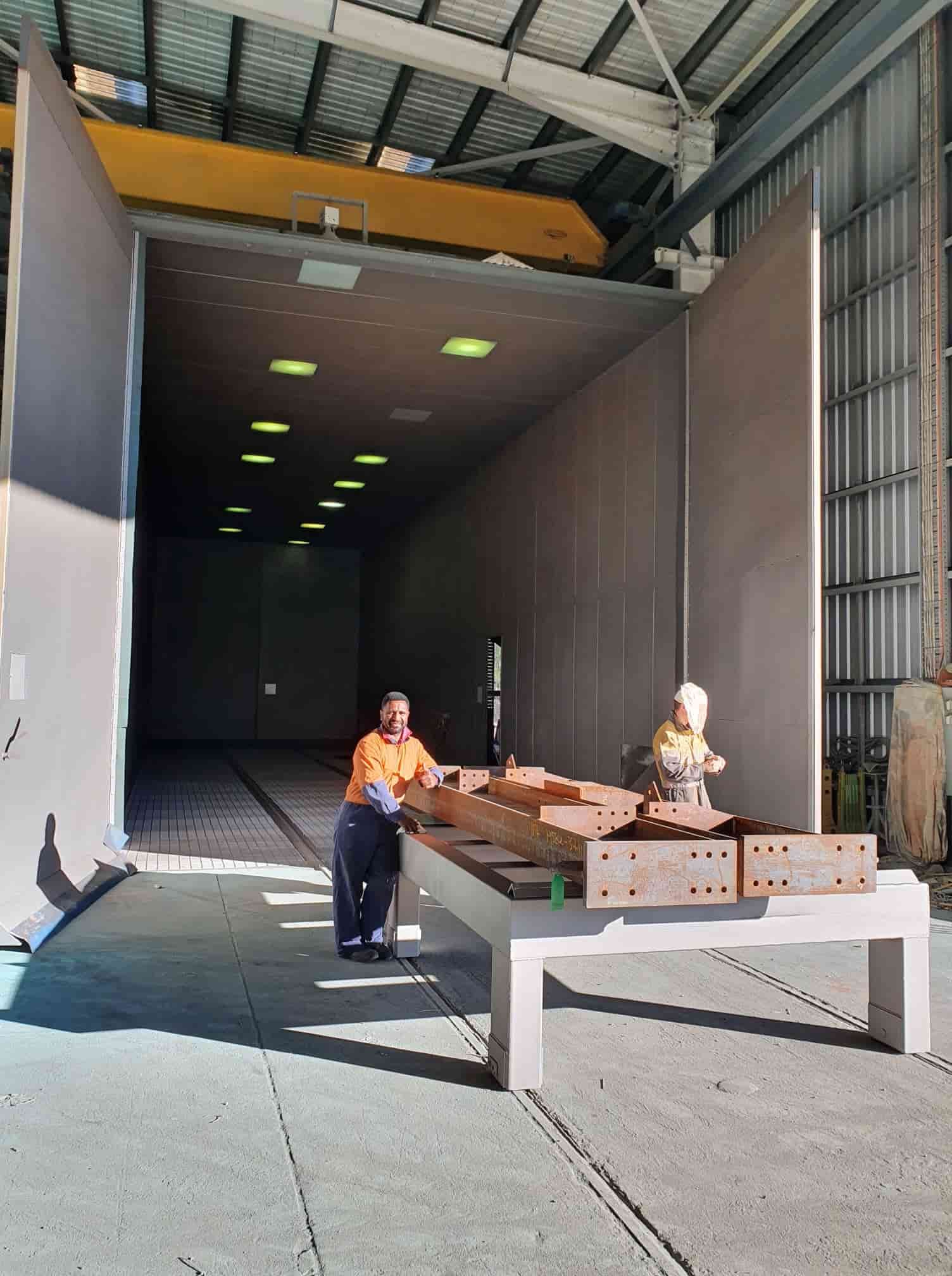 A Man is Sitting at a Table in a Factory — Waters Abrasive Blasting Services In Cairns, QLD