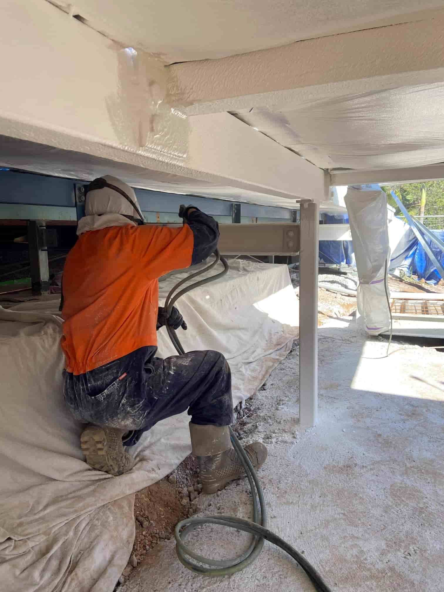A Man is Spraying a Wall With a Hose — Waters Abrasive Blasting Services In Shaw, QLD