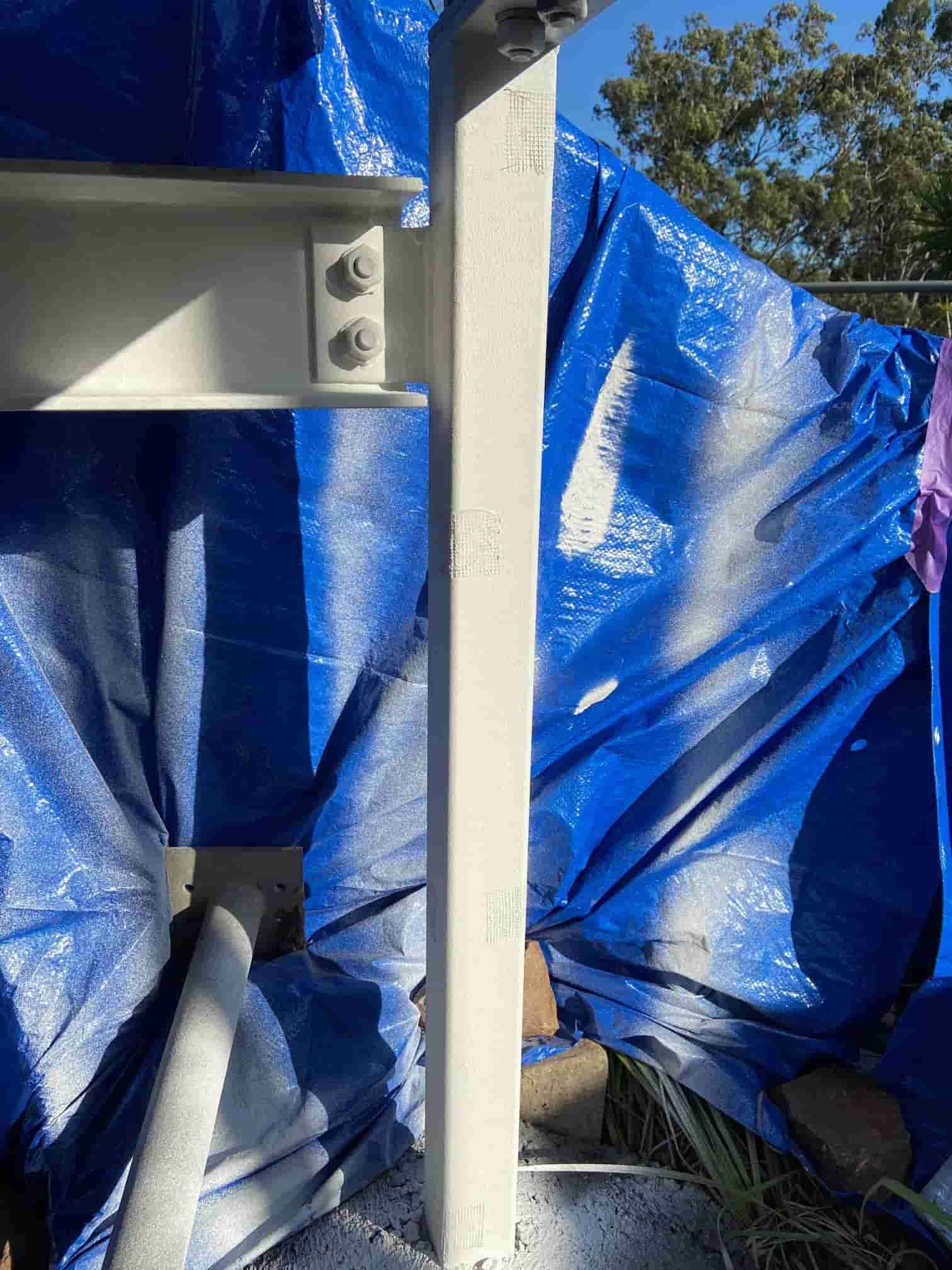 A White Pole is Sitting in Front of a Blue Tarp — Waters Abrasive Blasting Services In Townsville, QLD