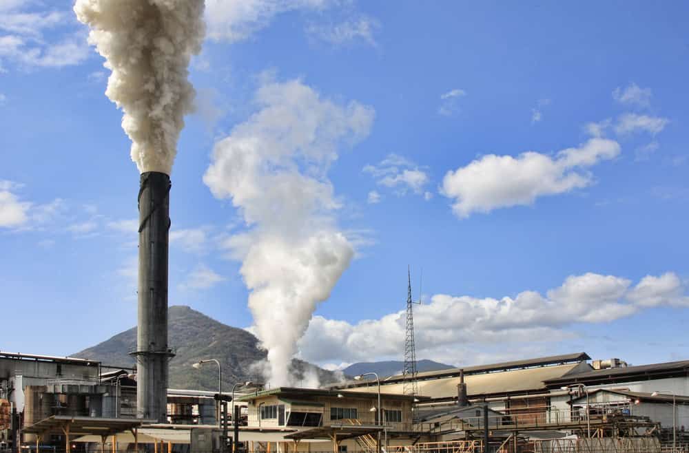 Smoke is Coming Out of a Chimney at a Factory — Waters Abrasive Blasting Services In Shaw, QLD