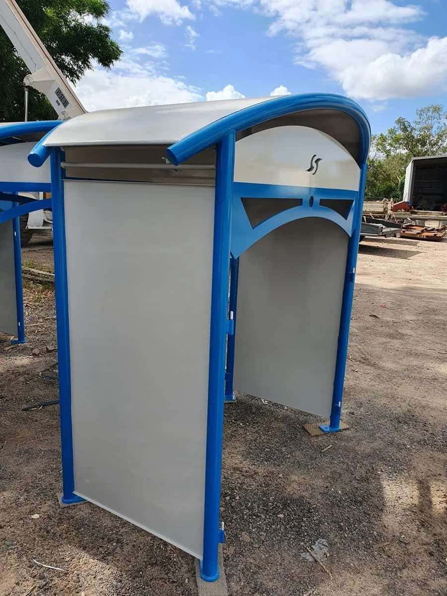 A Blue and White Bus Stop Shelter is Sitting in the Dirt — Waters Abrasive Blasting Services In Shaw, QLD