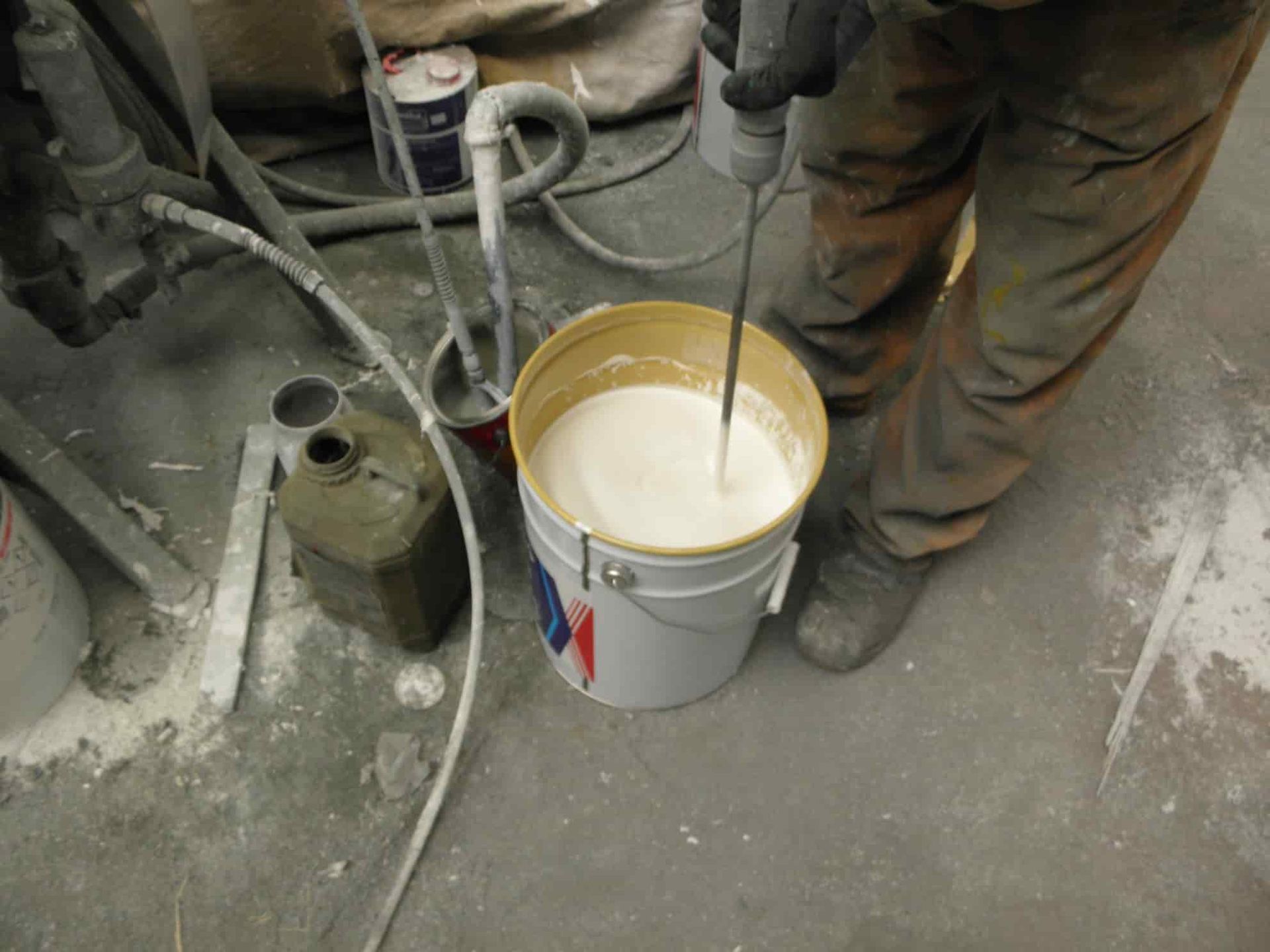 A Person is Mixing a White Liquid in a Bucket — Waters Abrasive Blasting Services In Shaw, QLD