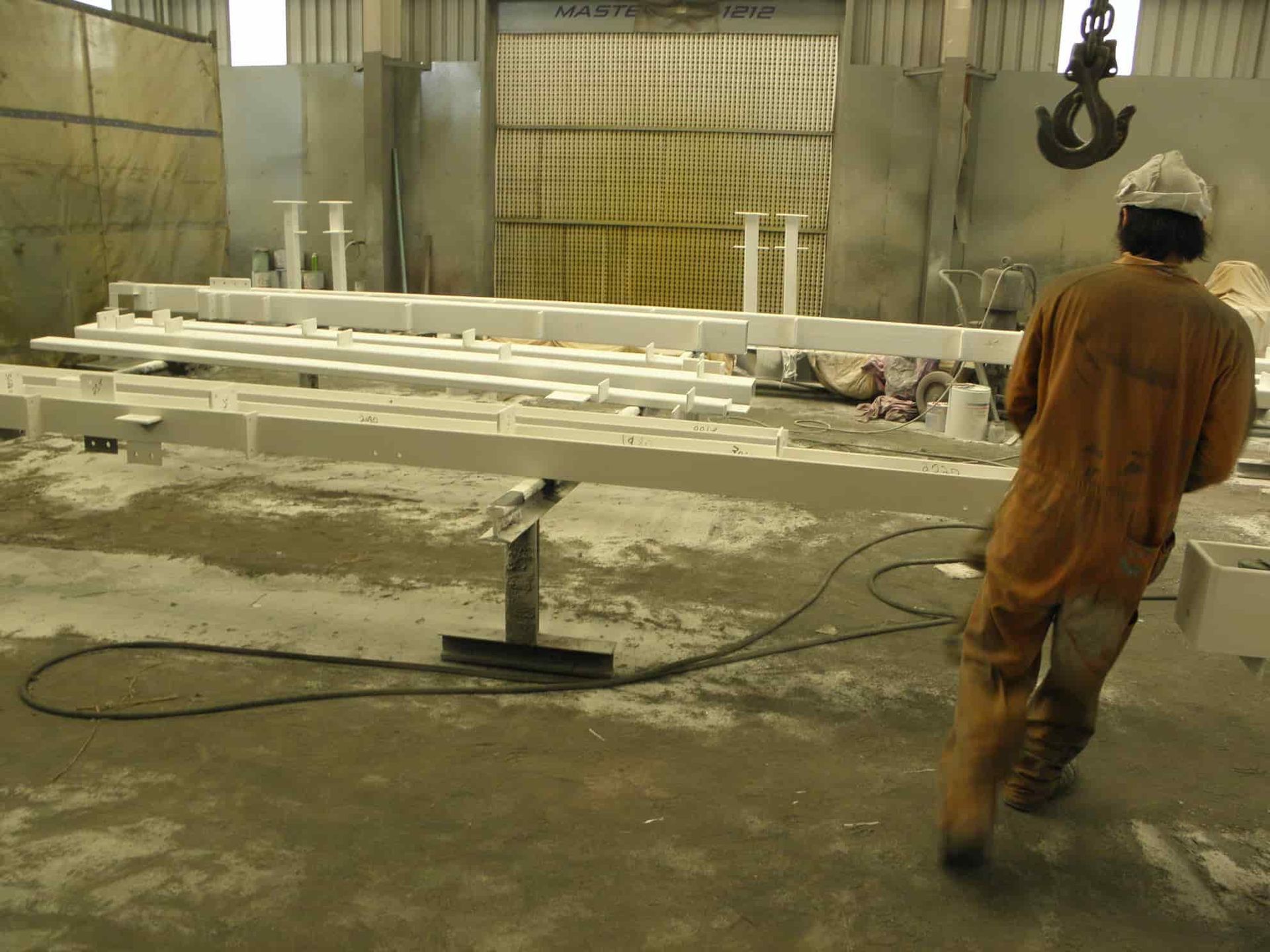A Man Wearing a Hard Hat is Standing in Front of a Crane — Waters Abrasive Blasting Services In Shaw, QLD