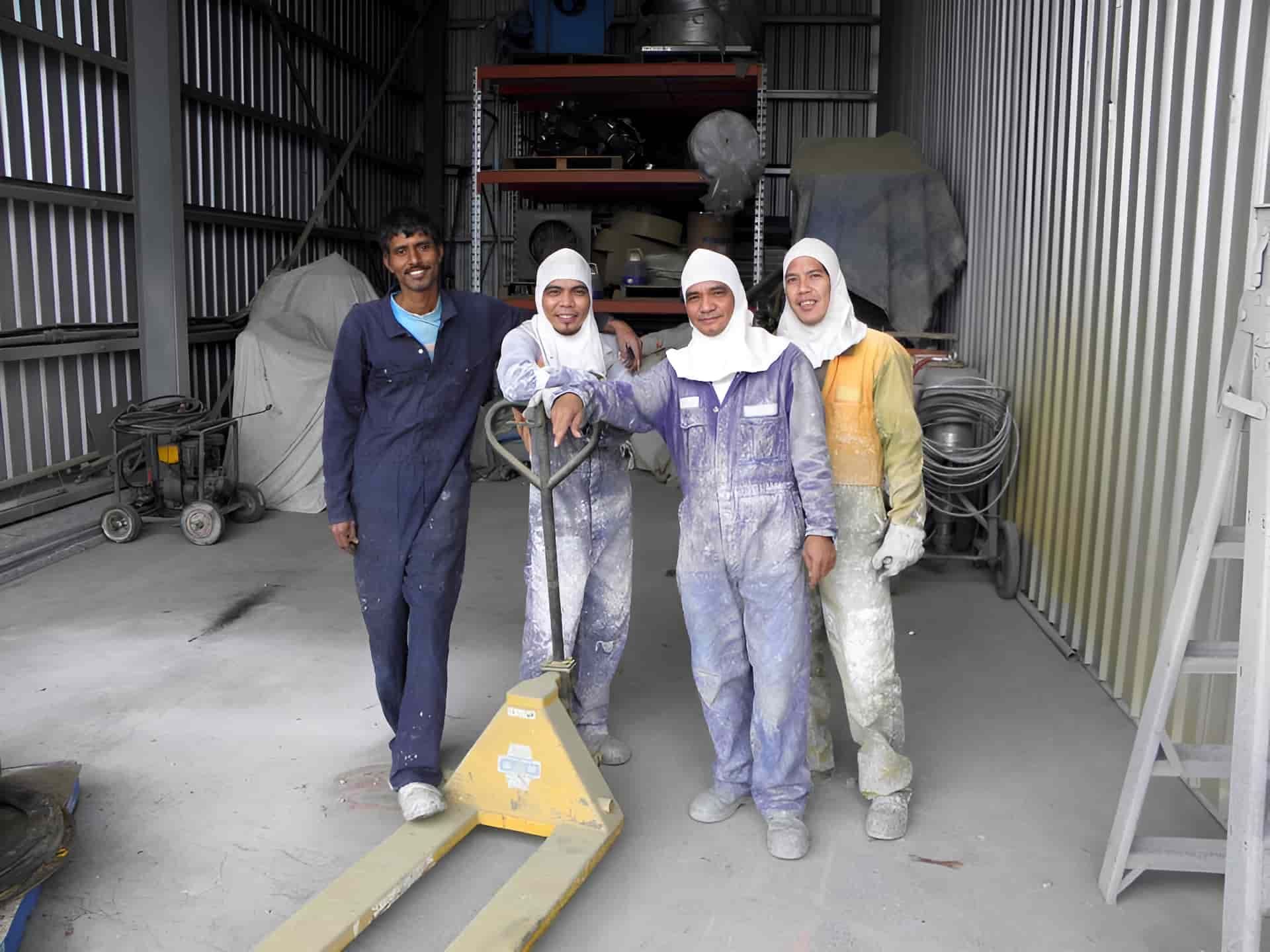 A Group of People Are Posing for a Picture in a Warehouse — Waters Abrasive Blasting Services In Rockhampton, QLD