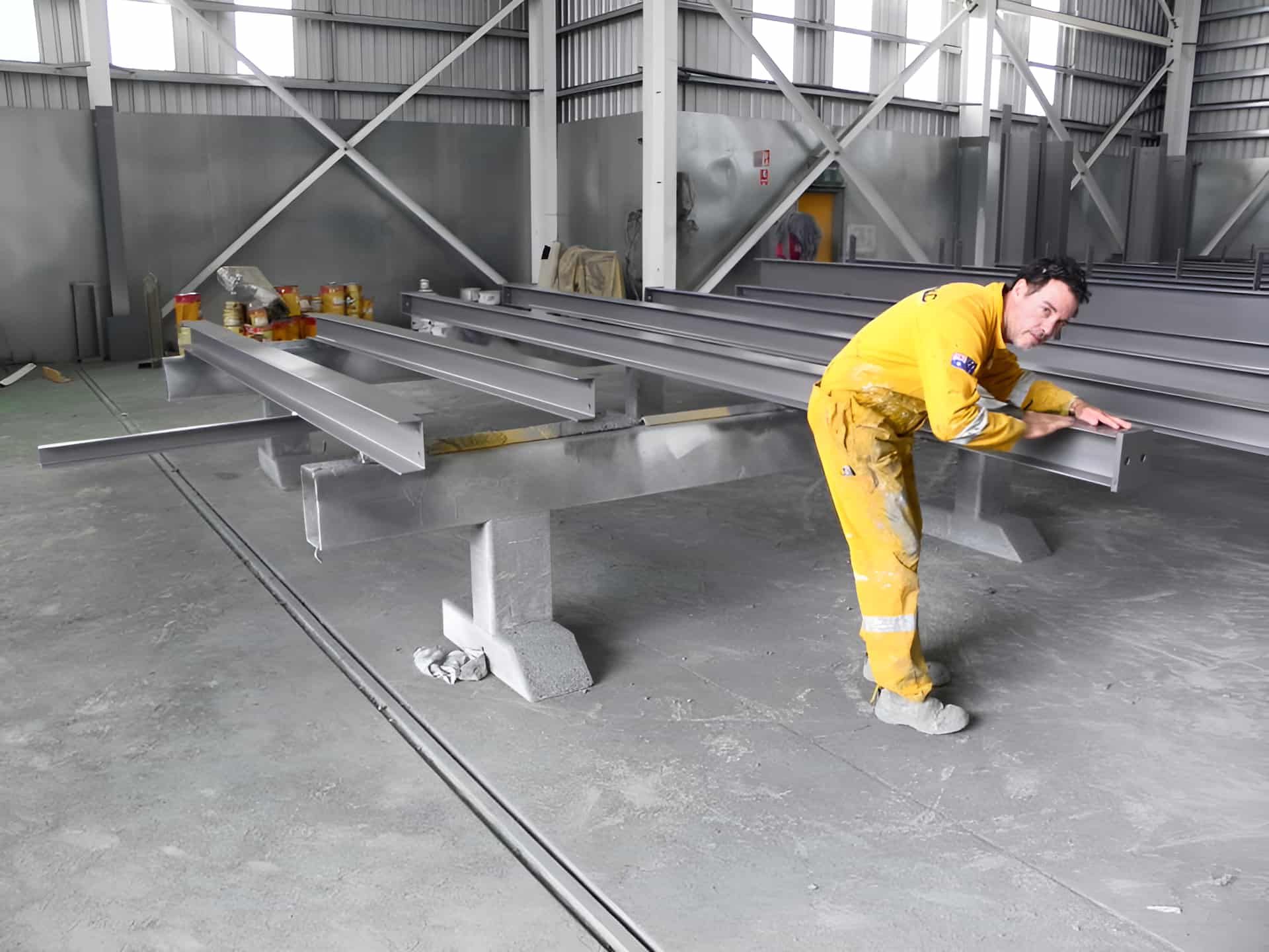 A Man in a Yellow Jumpsuit is Working on a Metal Structure — Waters Abrasive Blasting Services In Rockhampton, QLD