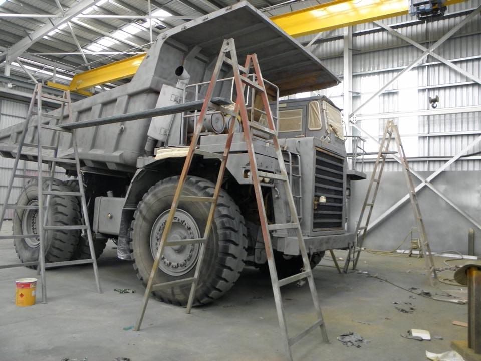 A Large Dump Truck is Sitting in a Warehouse With a Ladder on Top of It — Waters Abrasive Blasting Services In Shaw, QLD