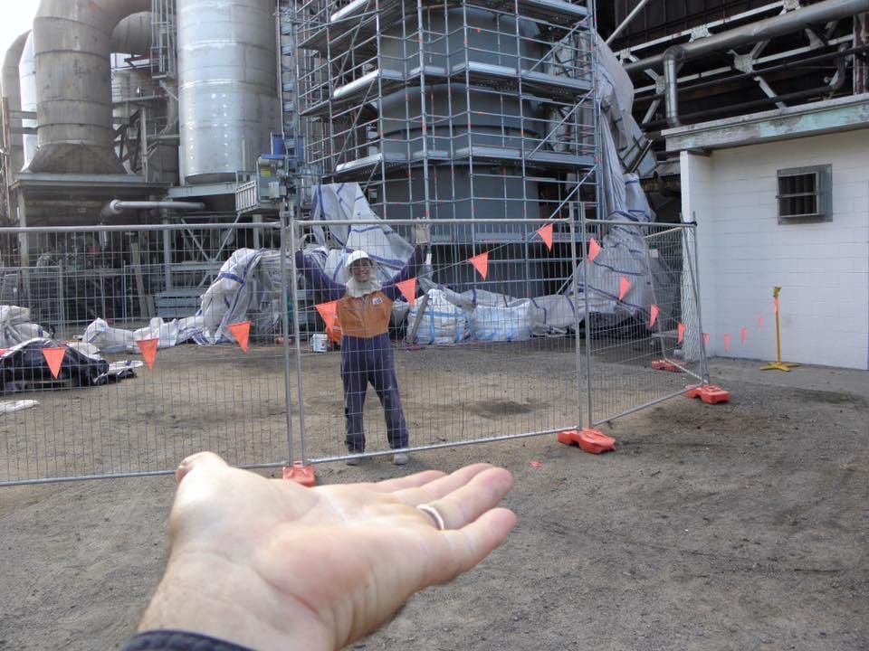 A Person's Hand is Reaching Out Towards a Man Standing Behind a Fence — Waters Abrasive Blasting Services In Shaw, QLD