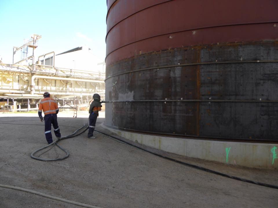 Two Men Are Standing Next to a Large Metal Tank — Waters Abrasive Blasting Services In Shaw, QLD