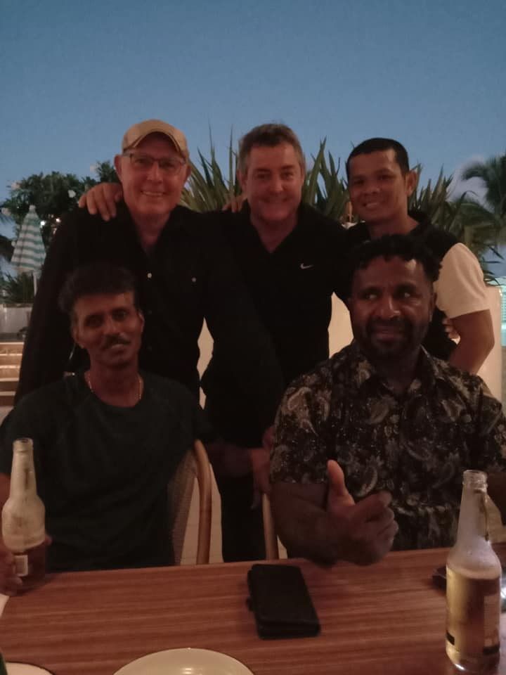 A Group of Men Are Posing for a Picture at a Table — Waters Abrasive Blasting Services In Shaw, QLD