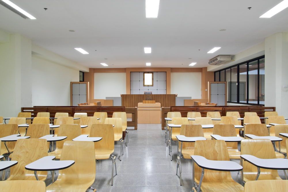 An Empty Classroom With Wooden Desks and Chairs — Waters Abrasive Blasting Services In Shaw, QLD