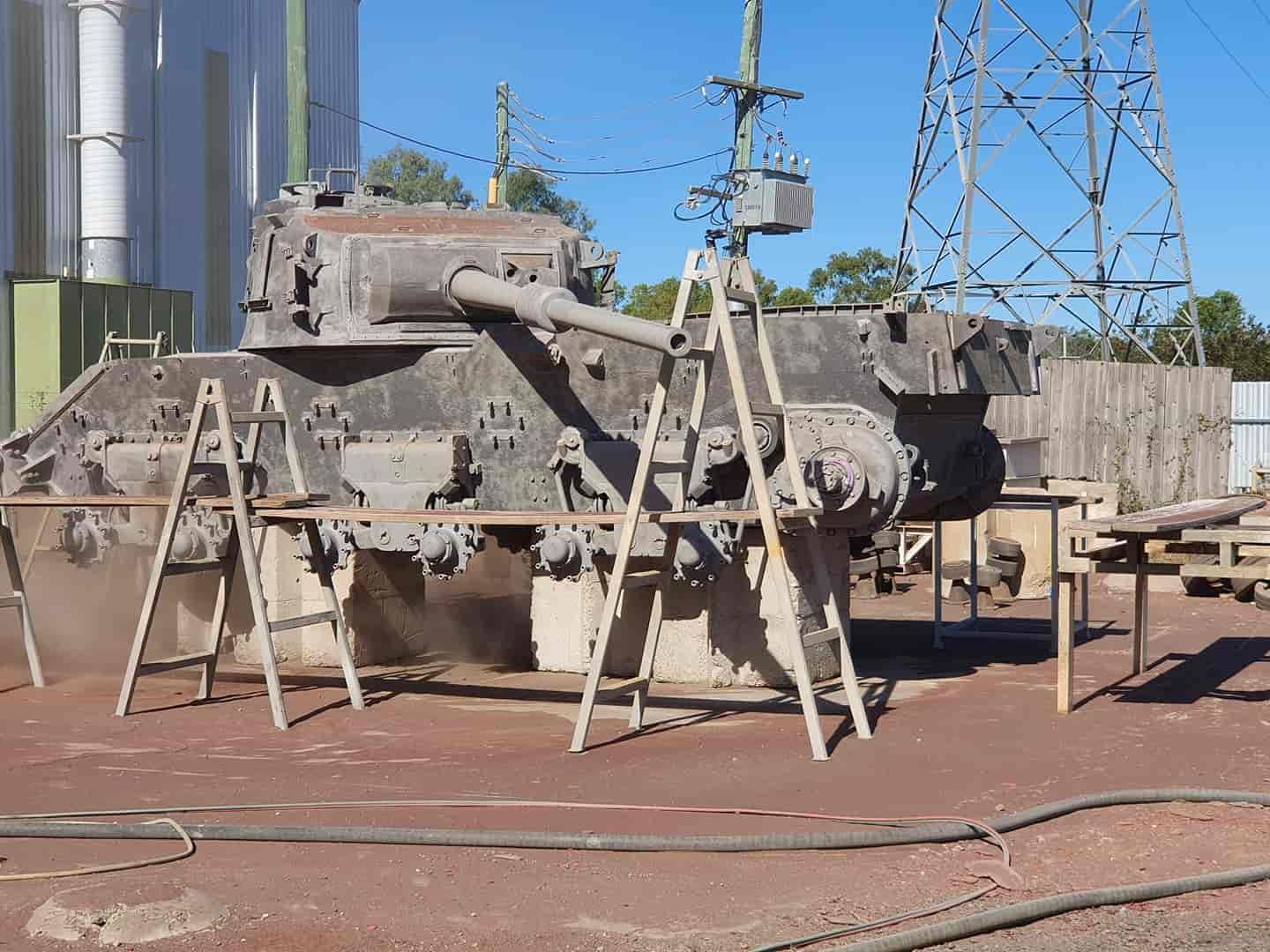 A Large Tank is Sitting on a Wooden Stand in a Field — Waters Abrasive Blasting Services In Whitsundays, QLD