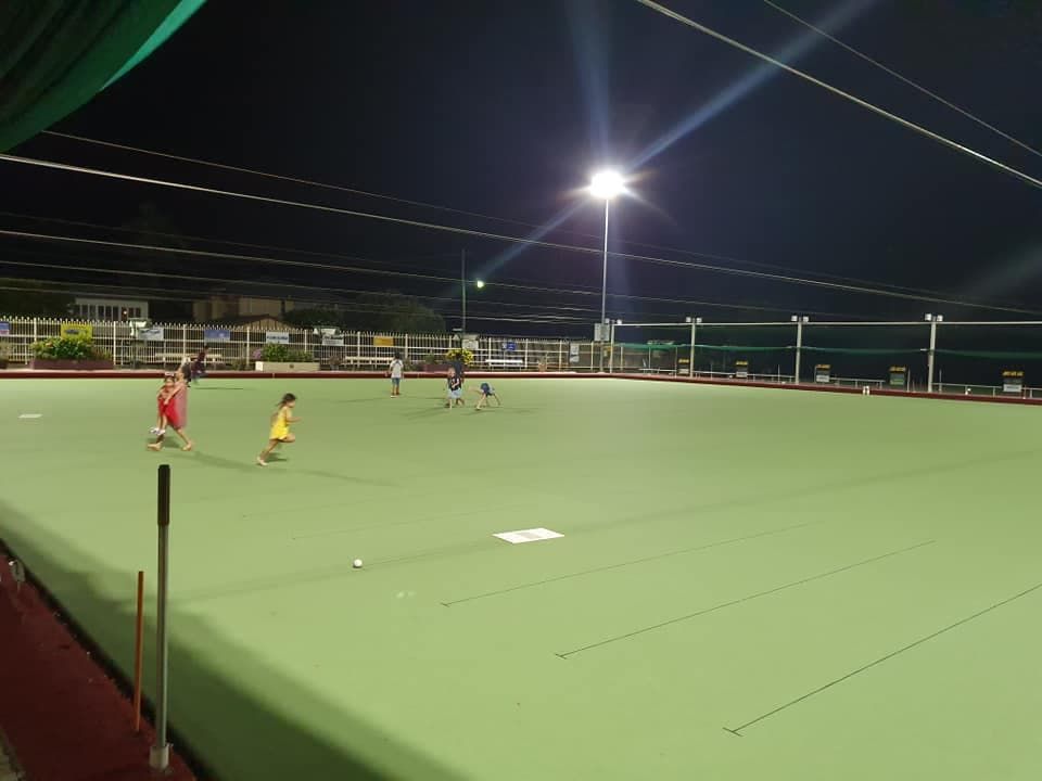 A Group of People Are Playing Soccer on a Green Field at Night — Waters Abrasive Blasting Services In Shaw, QLD